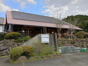 介護施設の建物外観。木造平屋建てで庭園と看板が見える